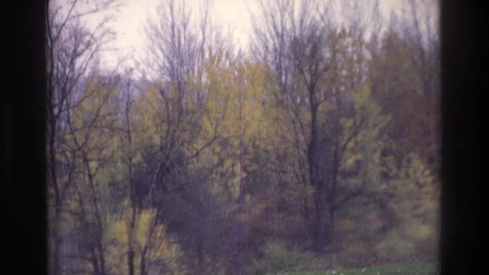 1975 Atlanta-area 8mm frame with leafing trees, distant hills, overcast light, and a central dark window divider.