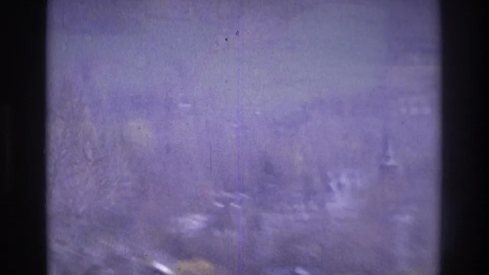 1975 Atlanta-area 8mm frame with bluish color cast, trees, faint distant structures, and visible film wear.