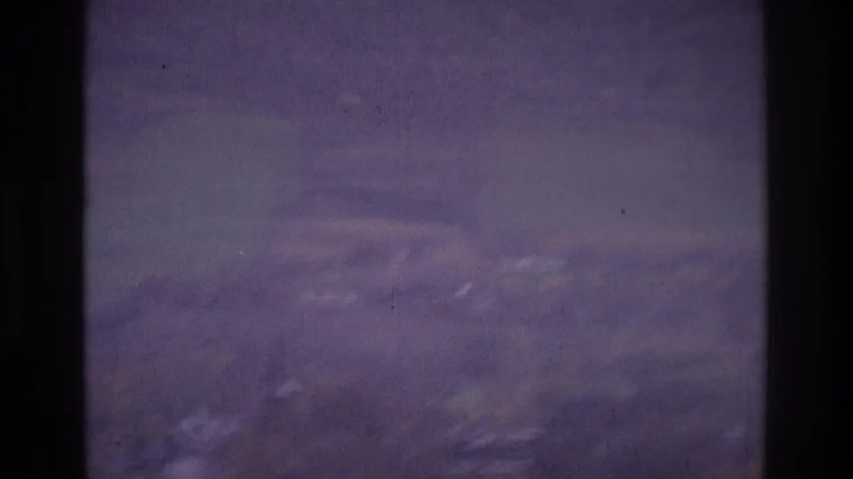 1975 Atlanta home-movie frame showing a blurred hillside or suburban view with bare branches and aged 8mm texture.