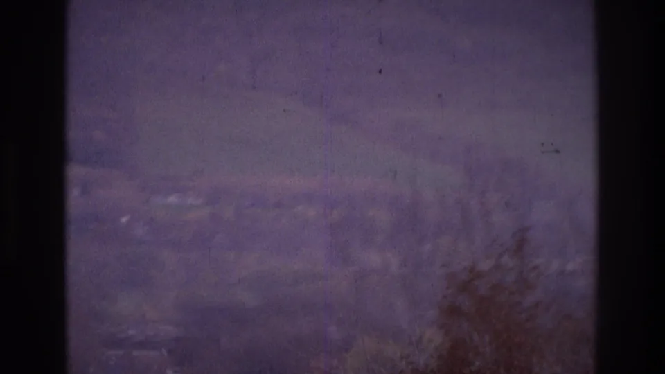 1975 Atlanta frame with a hazy suburban landscape, lower-corner trees, faint houses, and visible vertical film marks.