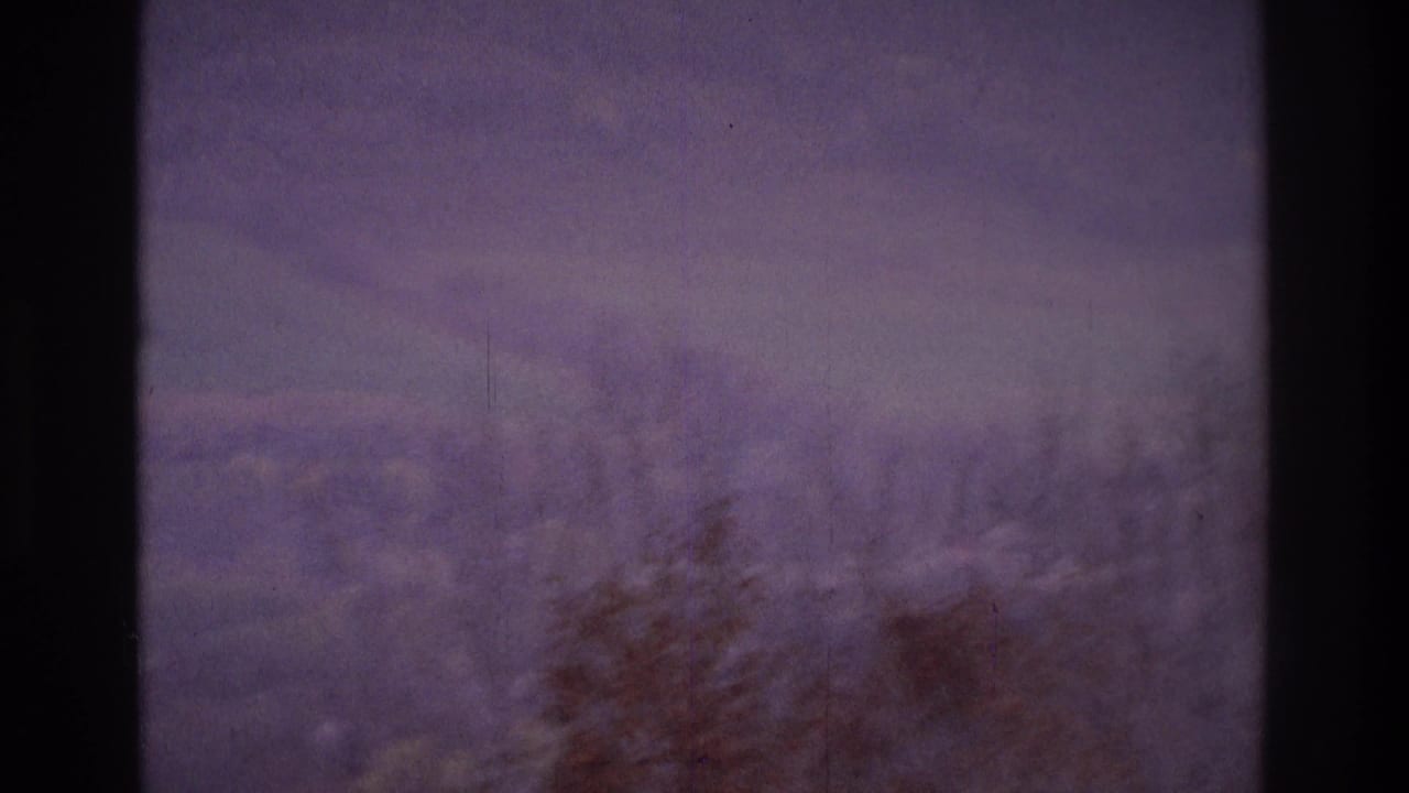 1975 Atlanta-area 8mm frame showing a hazy landscape through window glass, with bare trees and muted sky beyond the mullions.