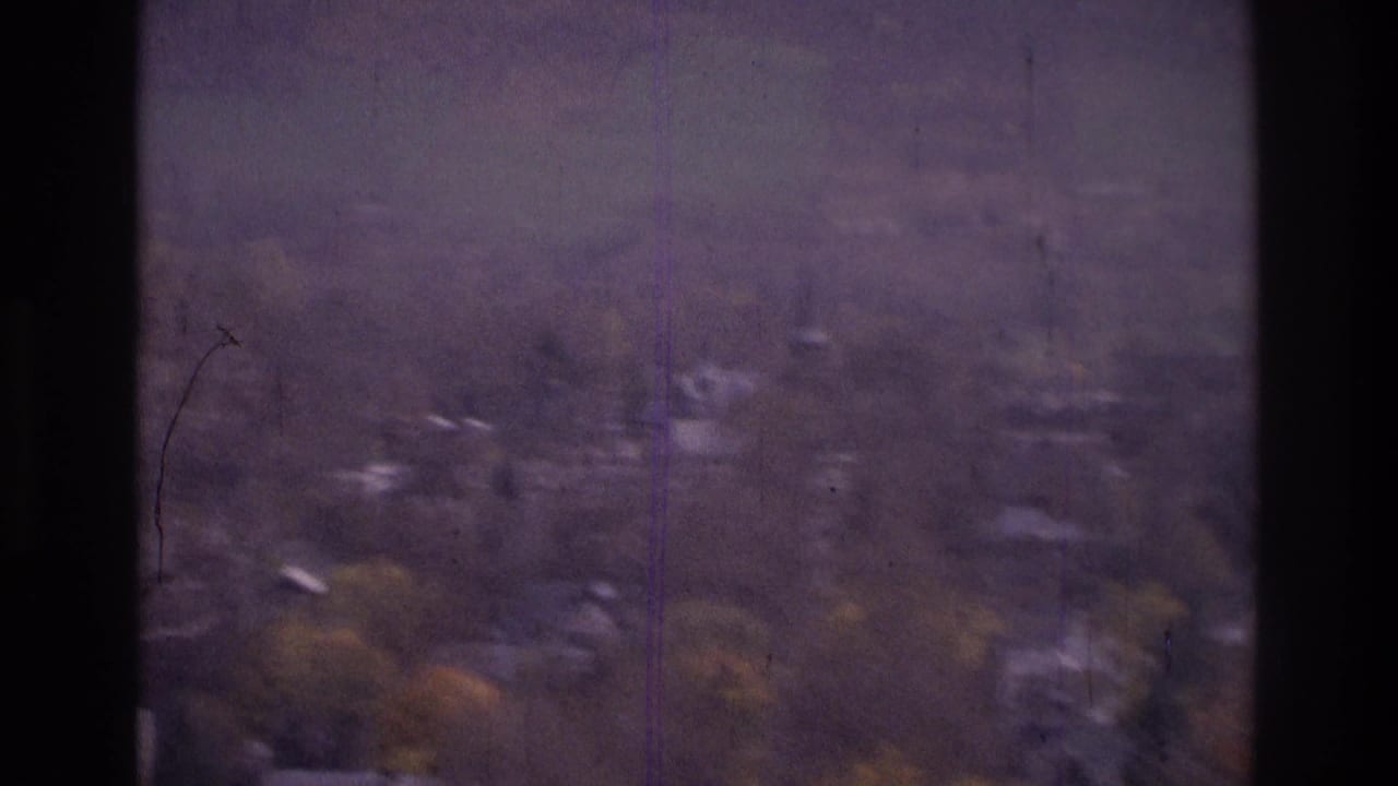 1975 8mm frame from the Atlanta, Georgia area showing a hazy elevated view of distant houses, trees, and low hills.