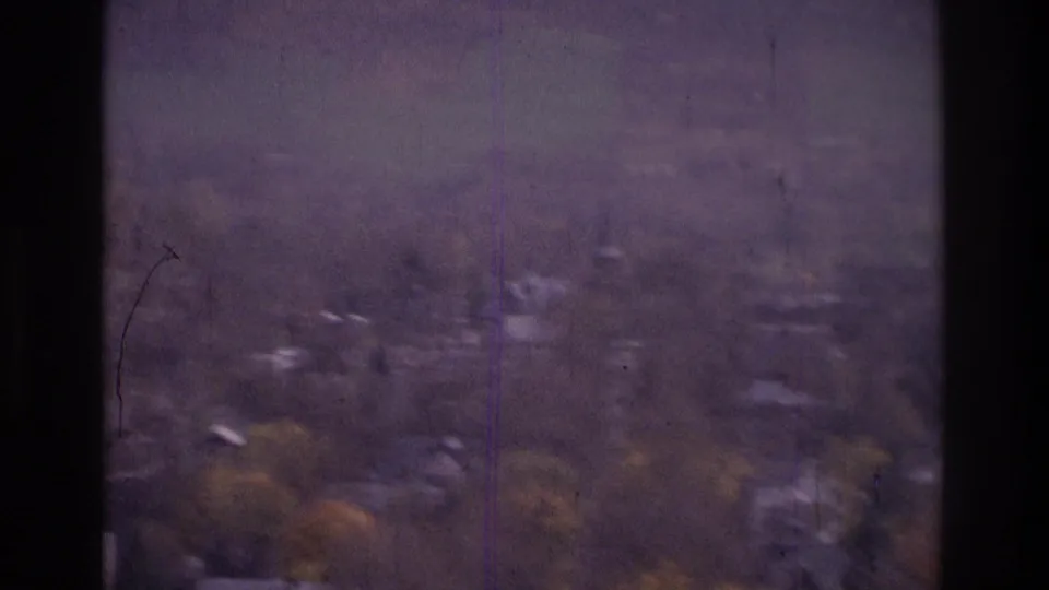 1975 8mm frame from the Atlanta, Georgia area showing a hazy elevated view of distant houses, trees, and low hills.