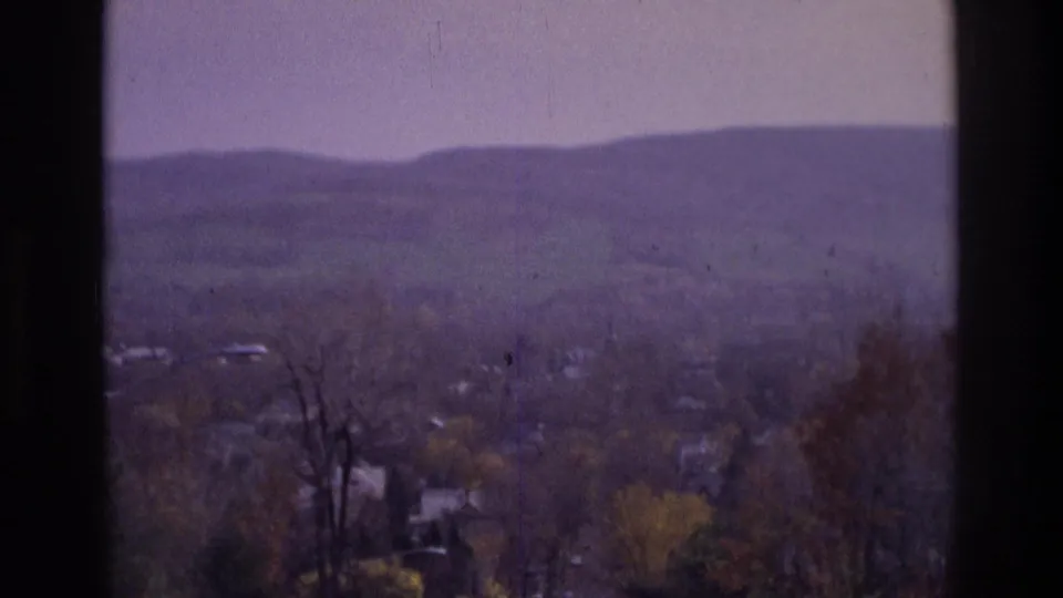 1975 Atlanta-area 8mm view over a residential valley, with foreground trees and low hills under a pale sky.