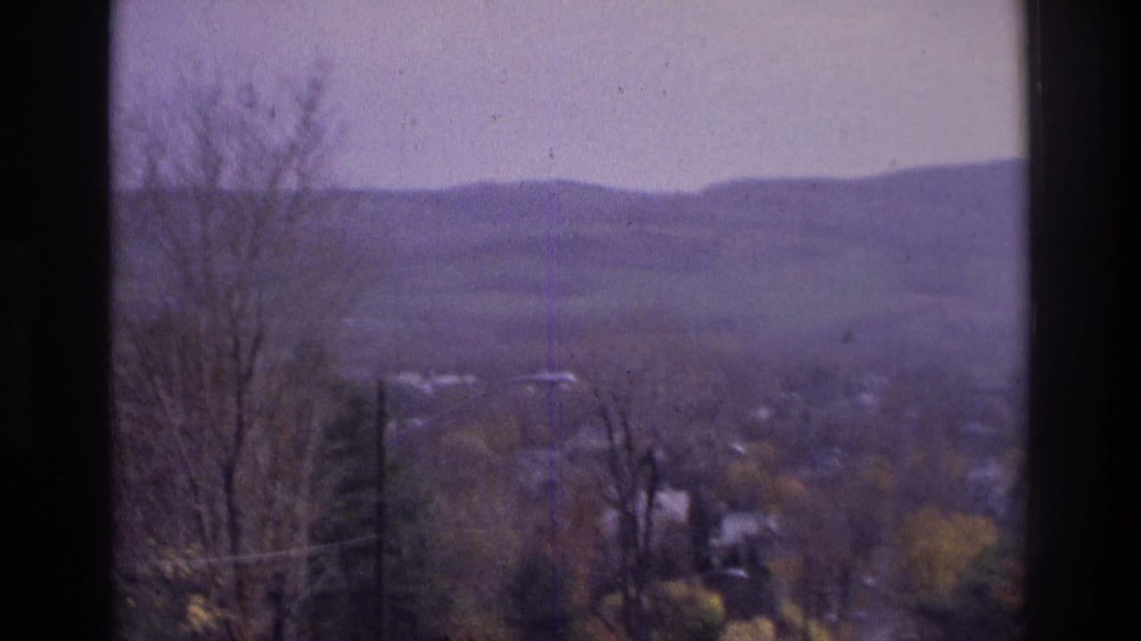 1975 Atlanta-area 8mm view of hazy distant hills, bare trees, valley houses, and dark window-frame edges.