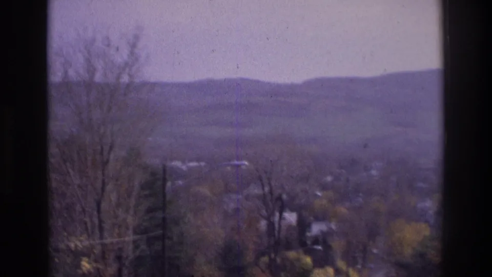 1975 Atlanta-area 8mm view of hazy distant hills, bare trees, valley houses, and dark window-frame edges.