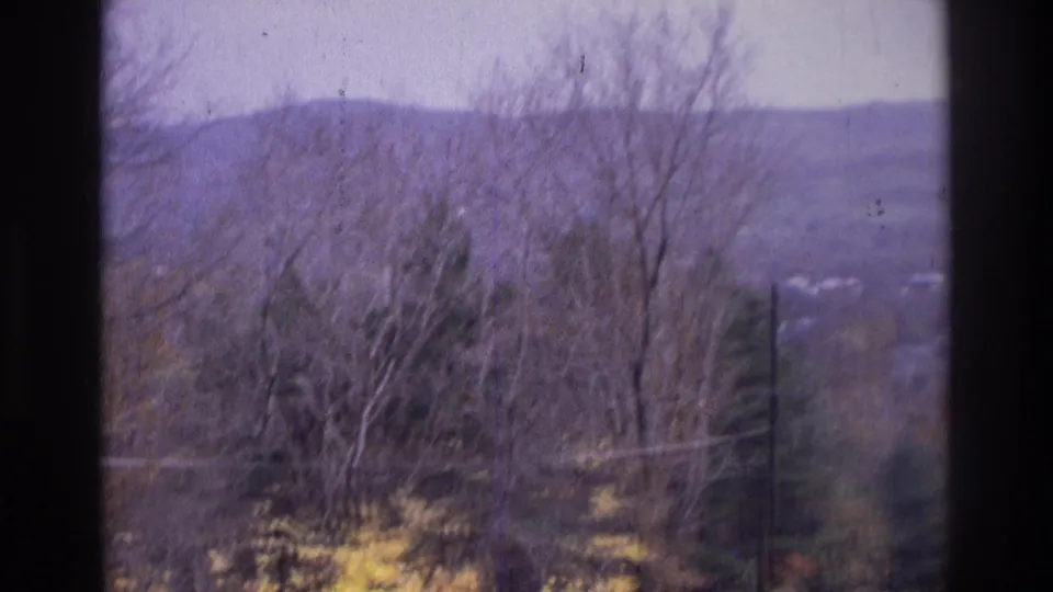1975 Atlanta-area 8mm landscape frame showing bare trees, distant hills, utility wires, and purple-tinted film wear.