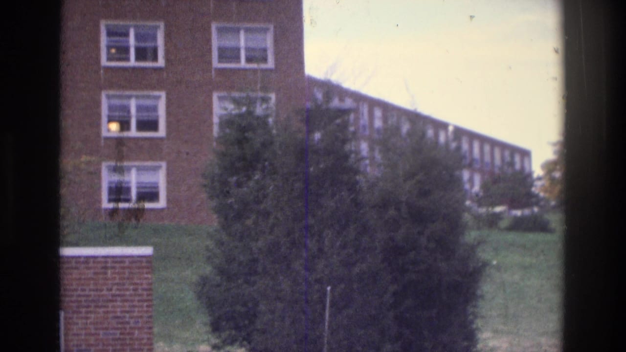 Atlanta 1975 8mm view of brick apartment buildings, a grassy slope, trees, and white-framed windows.