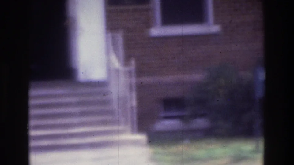 1975 Atlanta 8mm view of a brick building entrance with concrete steps, a white column, window, and grass.