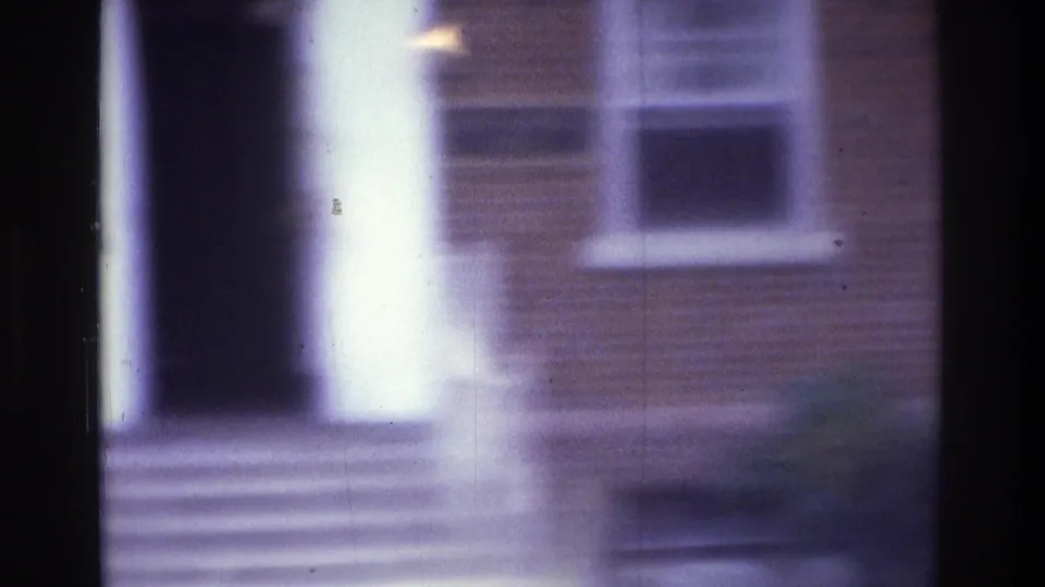 1975 Atlanta 8mm frame showing a white portico column, entrance steps, and brick facade with a white-trimmed window.