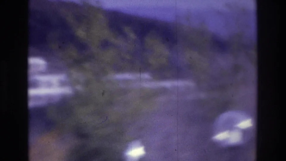 1975 Atlanta 8mm frame with trees, round streetlamp globes, distant hills, and pale building edges in a purple-tinted exterior view.