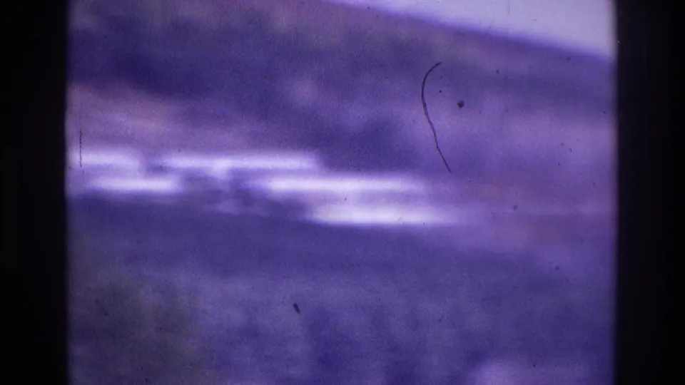 Soft-focus 1975 Atlanta home-movie frame showing an indistinct outdoor scene with purple color cast and dark film-edge borders.
