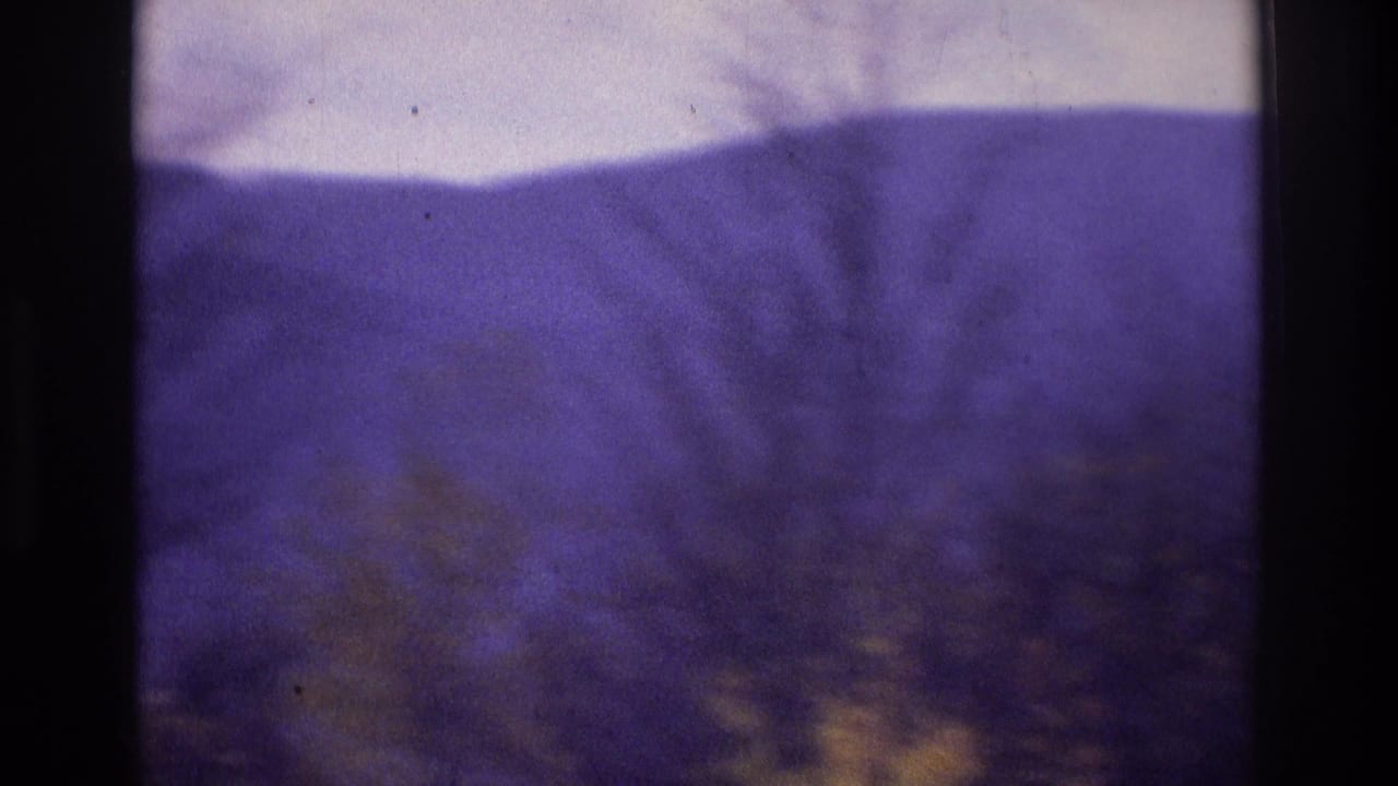Soft 8mm frame with purple-tinted rolling hills and indistinct wooded terrain, consistent with the Atlanta, Georgia 1975 clip metadata.
