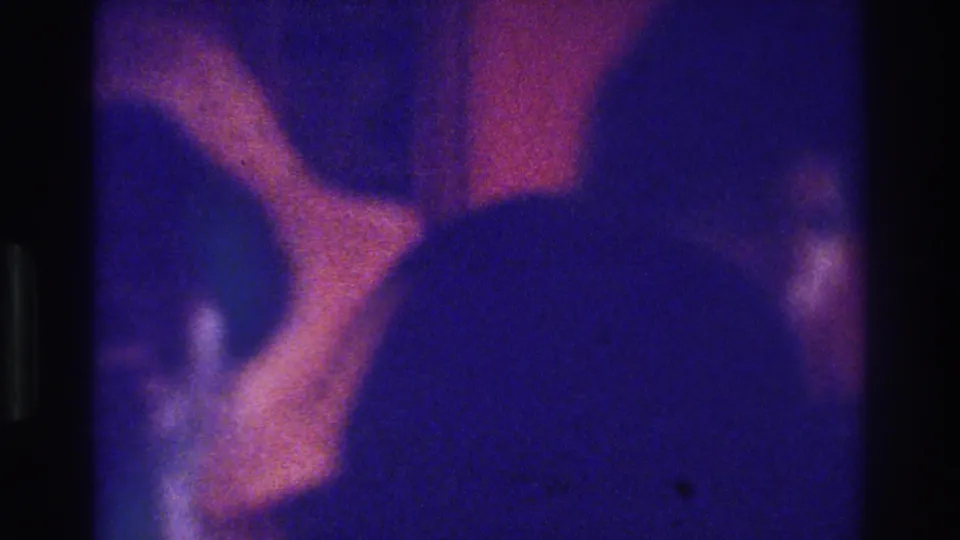 1975 Bronx 8mm frame with a prominent straw hat and partly visible adult women, blurred by grain and color shift.