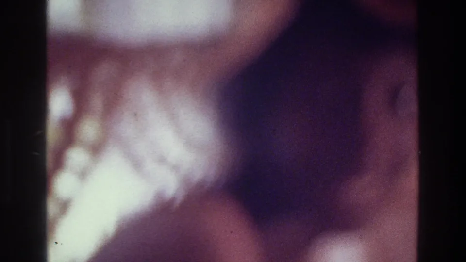 1975 Bronx 8mm frame with a heavily blurred close-up figure, purple color cast, low light, and visible film grain.