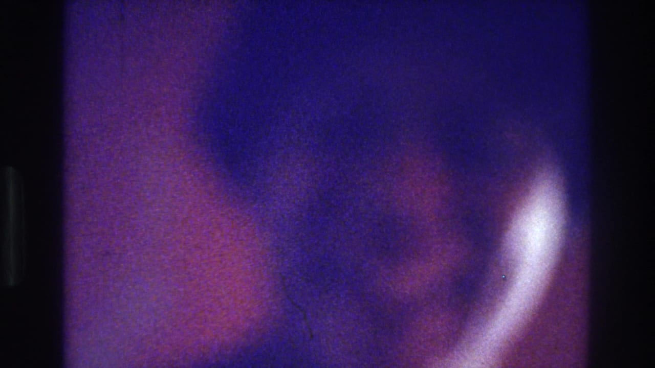 Color-shifted 8mm frame from the 1975 Bronx clip, showing a blurred person in close view without clear facial detail.