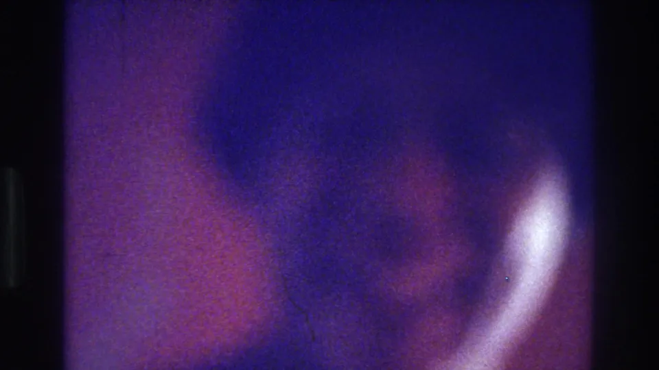 Color-shifted 8mm frame from the 1975 Bronx clip, showing a blurred person in close view without clear facial detail.