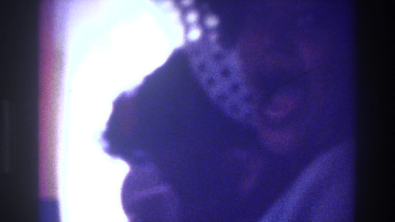 Soft, blue-purple close view of patterned fabric or hat with bright light leak at the left edge.