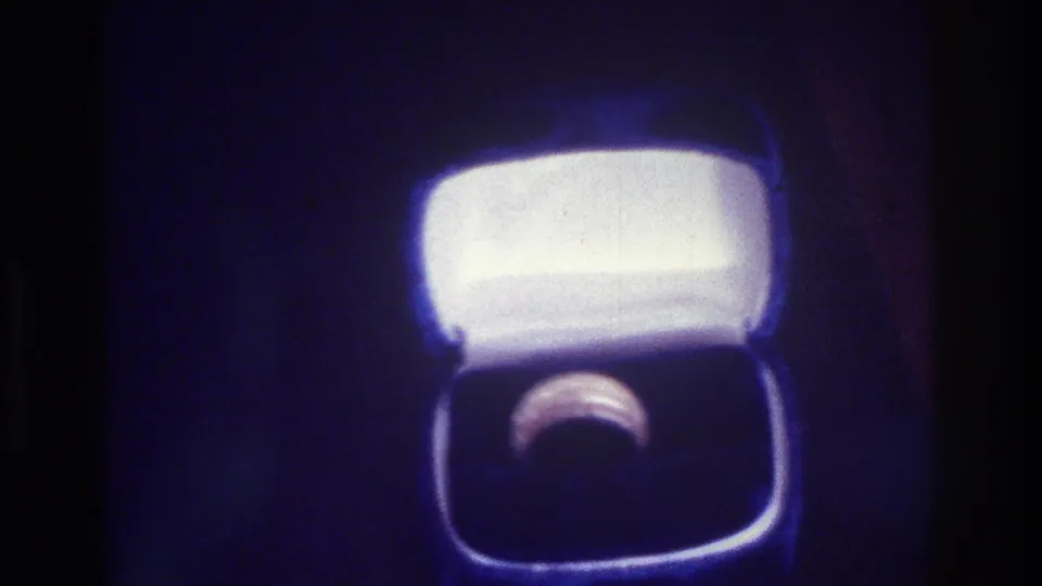 1975 Bronx 8mm frame showing a ring in an open white-lined box under dramatic blue-tinted lighting.