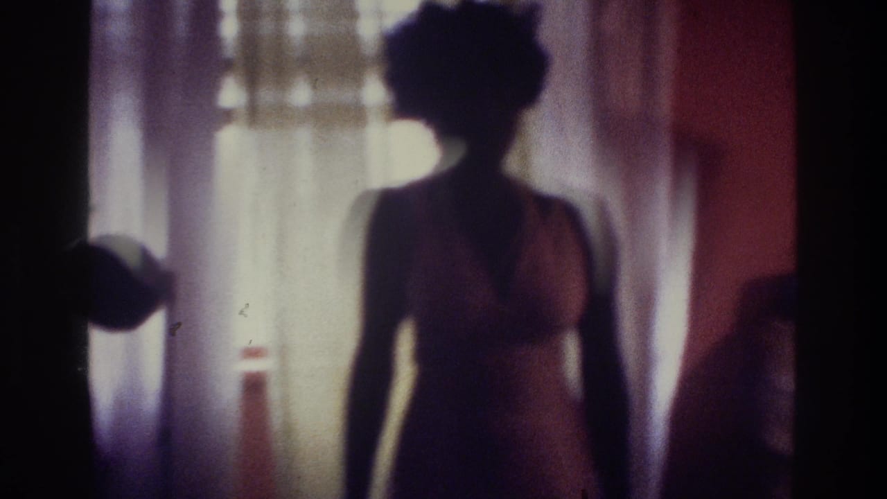 1975 Bronx home-movie frame showing a dark silhouette of a woman in a swimsuit near a bright curtained window.
