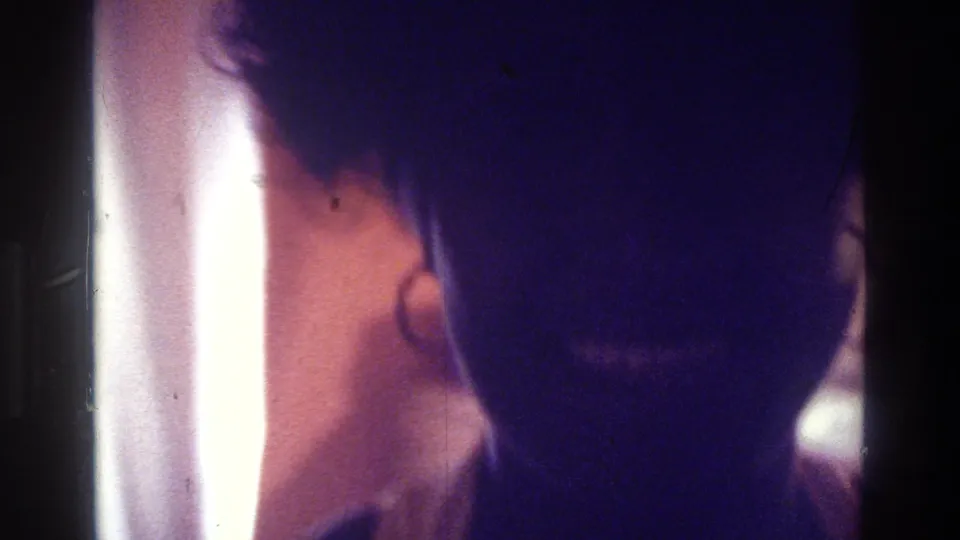 1975 Bronx frame showing a woman in silhouette, with hair outline and hoop earring visible beside bright interior light.