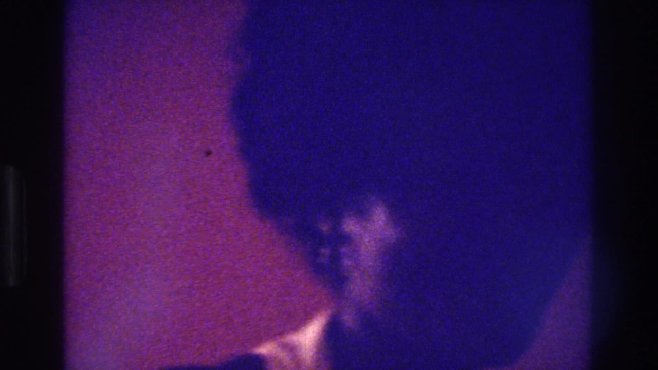 Dark, blue-purple frame with a woman's hair and partial face near the right side.
