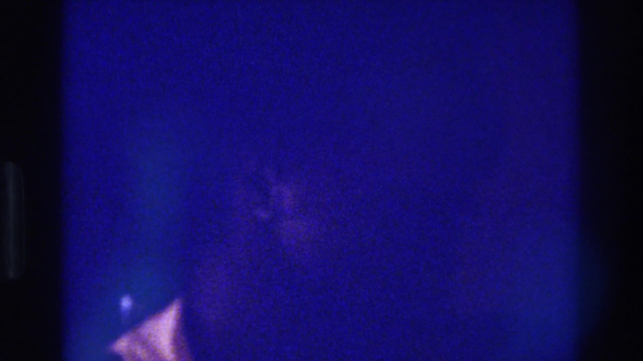 1975 Bronx 8mm frame with deep blue cast, grain, and an indistinct partial person in low light.