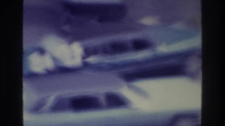 1975 Bronx 8mm frame with blue-purple color shift, soft focus, dark film edges, and vague shapes that may indicate a waterfront scene.