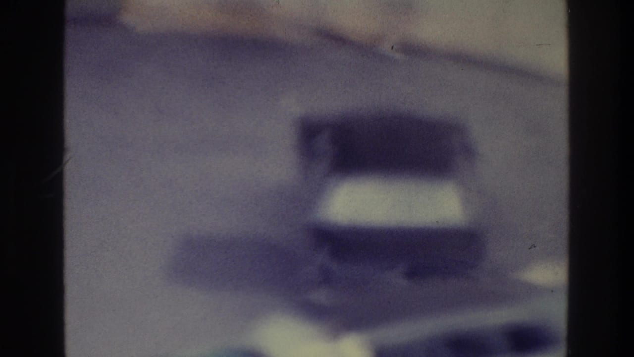 A 1975 Bronx road view shows an indistinct vehicle shape through soft focus, grain, and strong blue-purple color shift.
