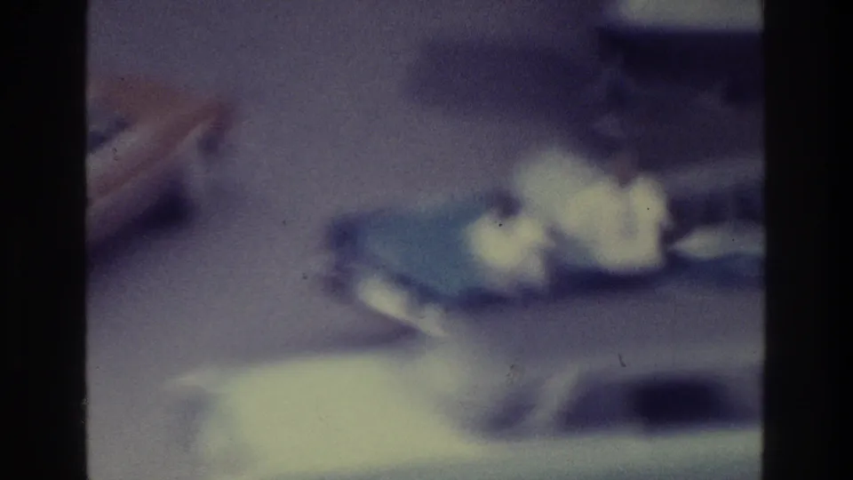 The final 1975 Bronx frame shows an indistinct car shape and bright foreground blur within a grainy, blue-purple 8mm street view.