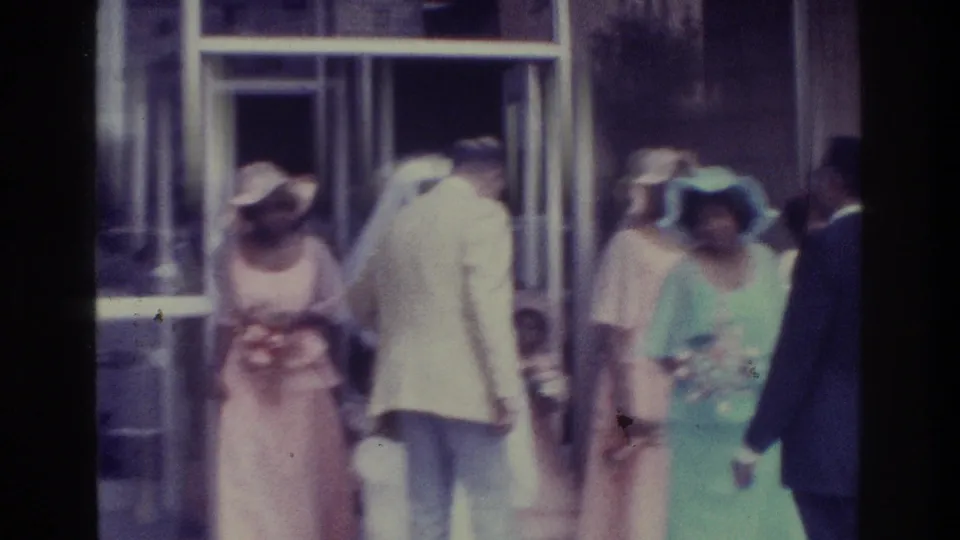 Bronx wedding exit scene with attendants in pink and mint dresses, a bride in white and suited guests near the chapel entrance.