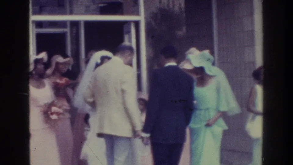 1975 Bronx home-movie view of a bride, attendants and suited guests moving through the chapel exit area.