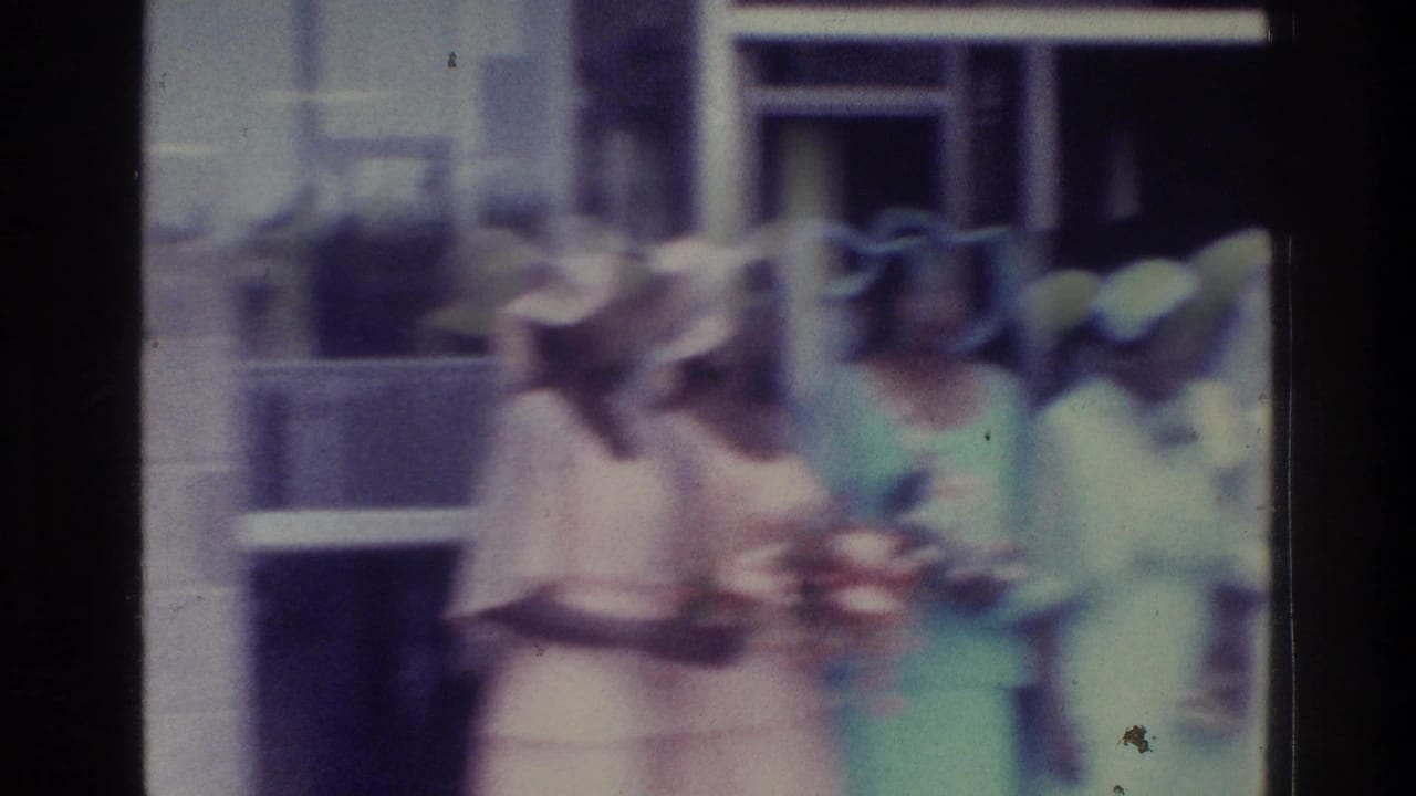 Bridesmaids in pink and mint dresses stand together, one holding a bouquet.