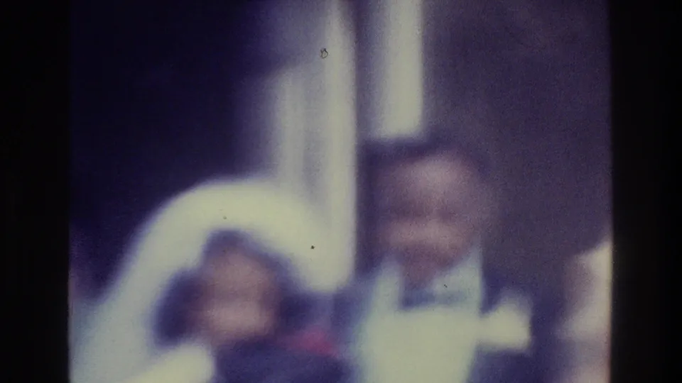 Blurred 1975 Bronx home-movie frame with the bride low in frame and the groom standing beside her indoors.