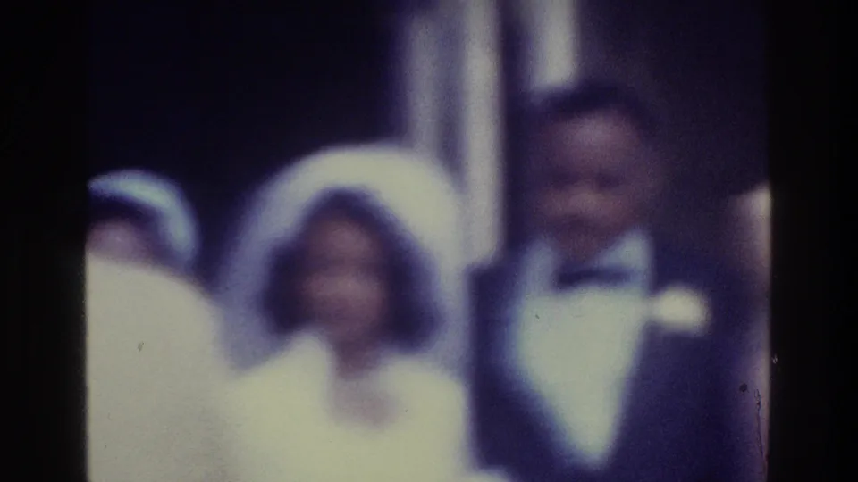 Soft 8mm wedding frame showing the bride in a veil and the groom in a tuxedo, with a guest partly visible beside them.