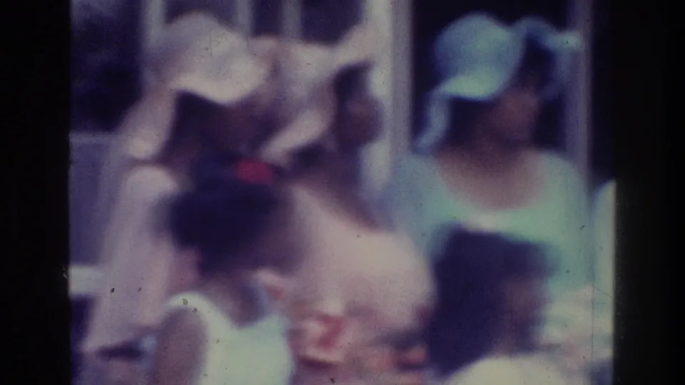 The final frame shows a close grouping of wedding guests, including women in hats and pale clothing, with the bride partly obscured within the soft 8mm image.