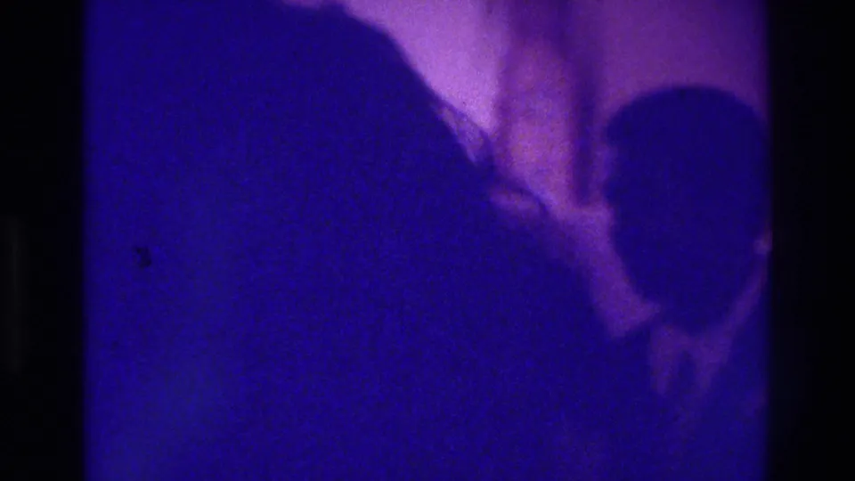 The final 1975 Bronx wedding frame shows dark guest silhouettes and a pale veil or gown shape in a low-exposure 8mm interior.