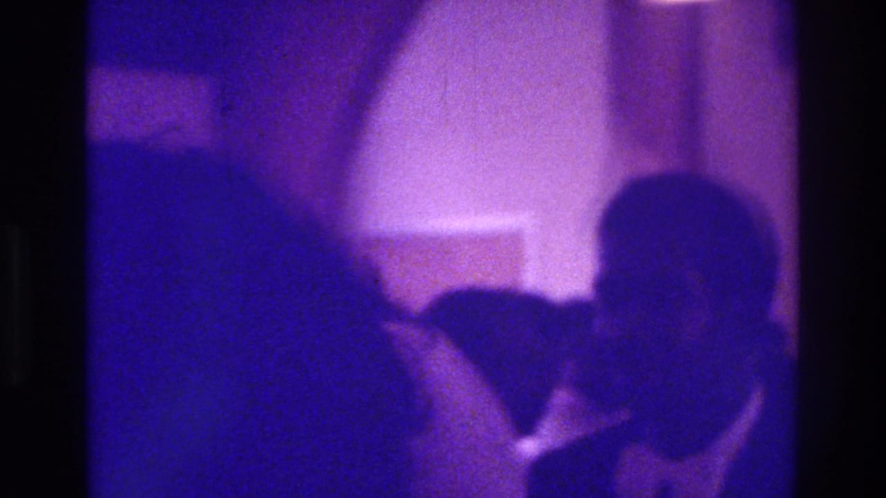 Dark silhouettes of formally dressed guests in a purple low-light interior.