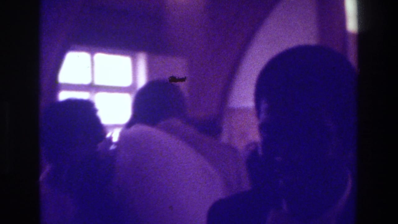 1975 Bronx church interior with congregants in silhouette against bright windows, seen in purple-tinted 8mm footage.