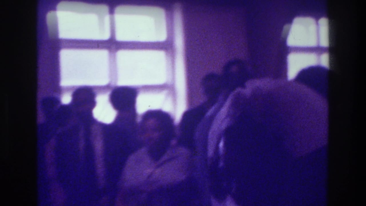 Crowded church room with figures standing near bright windows.