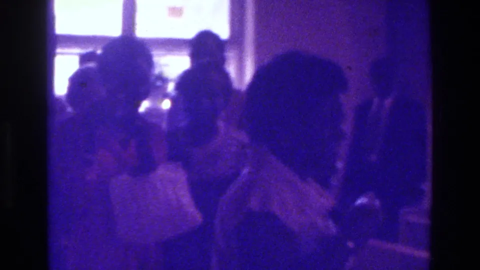 Soft 8mm view of a Bronx church gathering with seated and standing congregants beneath bright window light.