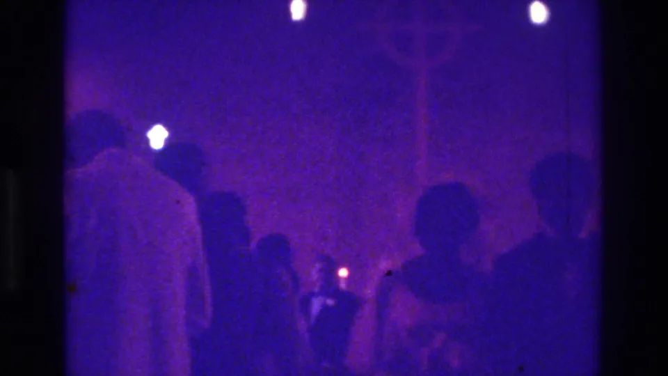1975 Bronx 8mm view from within the congregation, with standing and seated figures silhouetted against candlelight.