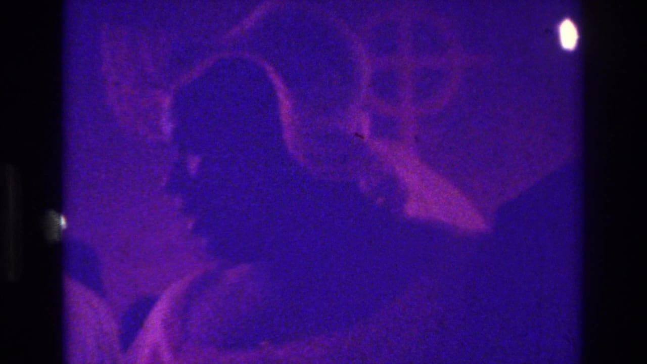 A dark foreground silhouette partially blocks the 1975 Bronx church wedding procession, with guests and soft purple-blue exposure behind.