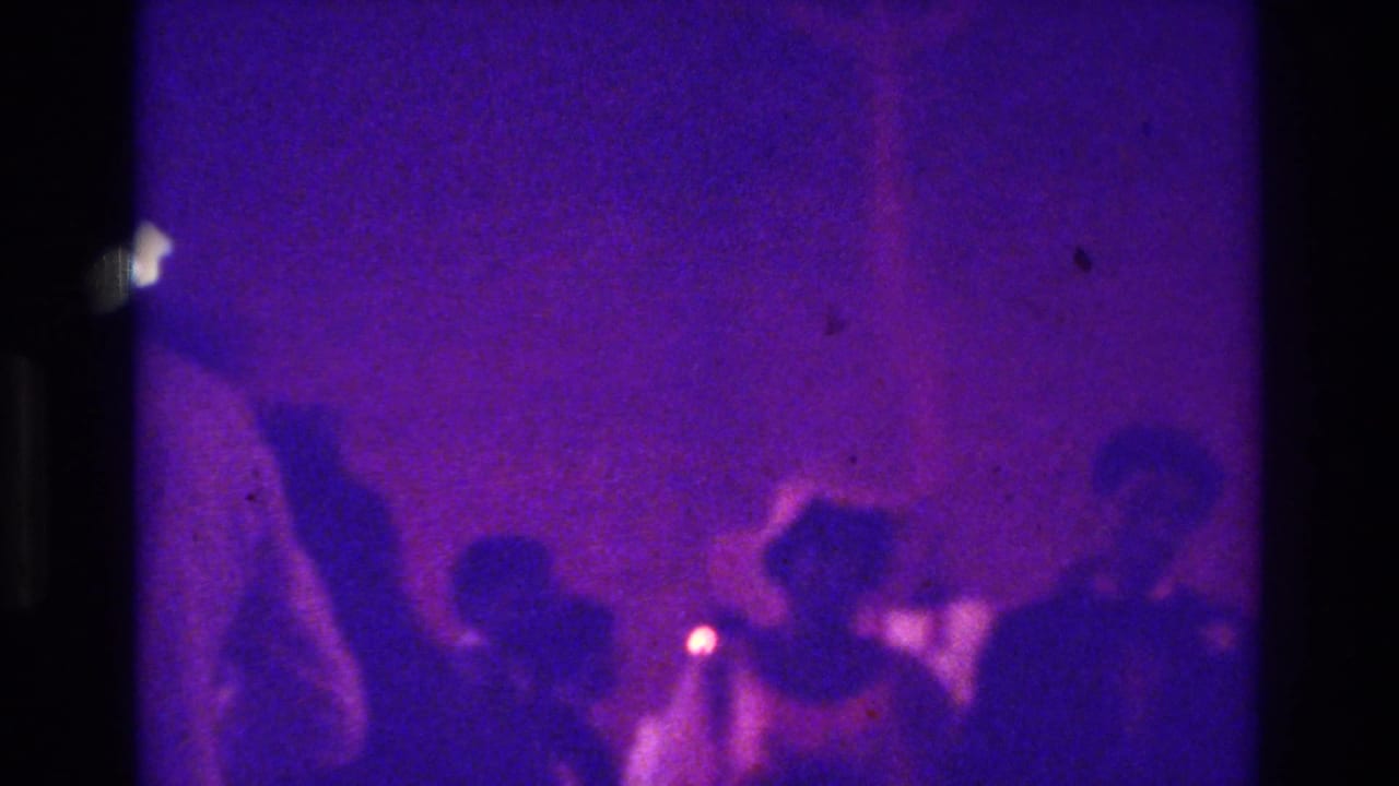1975 Bronx 8mm wedding footage showing a crowded church area with guests in silhouette under a strong purple color cast.