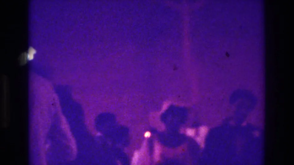 1975 Bronx 8mm wedding footage showing a crowded church area with guests in silhouette under a strong purple color cast.