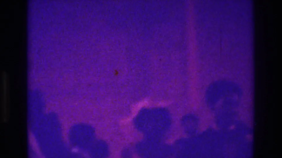 Soft 8mm frame from a 1975 Bronx church wedding showing guests and wedding-party figures moving through a crowded exit area.