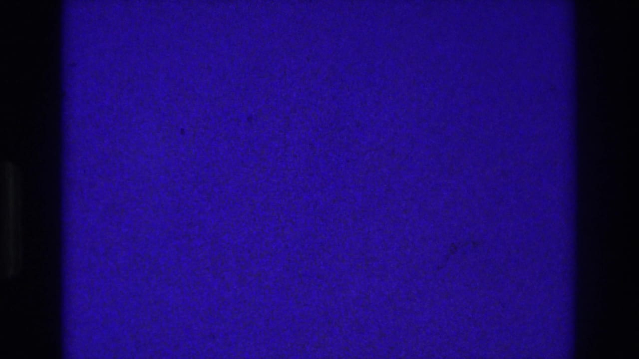 Mostly blue-purple film frame with dark vertical bars and minimal visible detail.