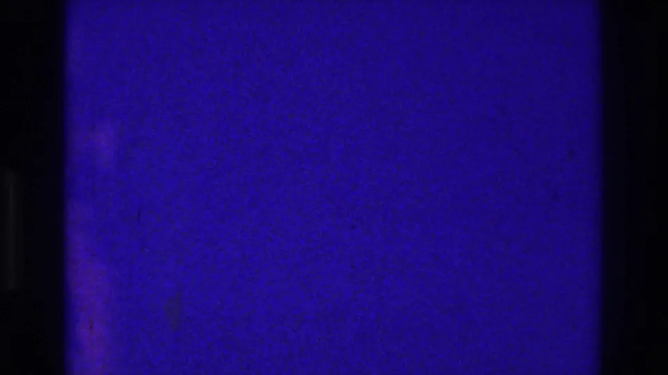 1975 Bronx 8mm home-movie frame showing blue-purple film texture, scratches, a horizontal exposure change, and no clear subject detail.