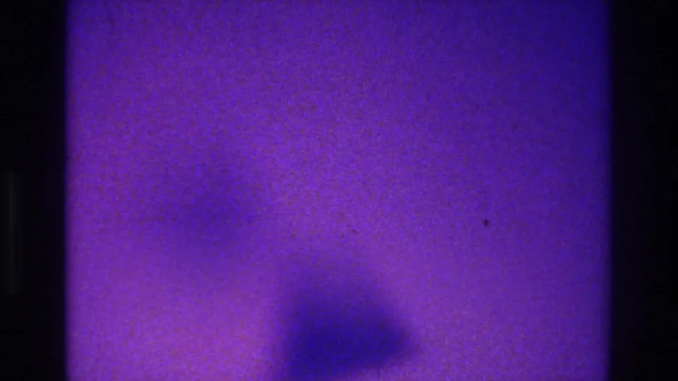 1975 Bronx 8mm frame with purple-blue cast, grain, and an indistinct dark form near the lower edge that may be a person or shadow.