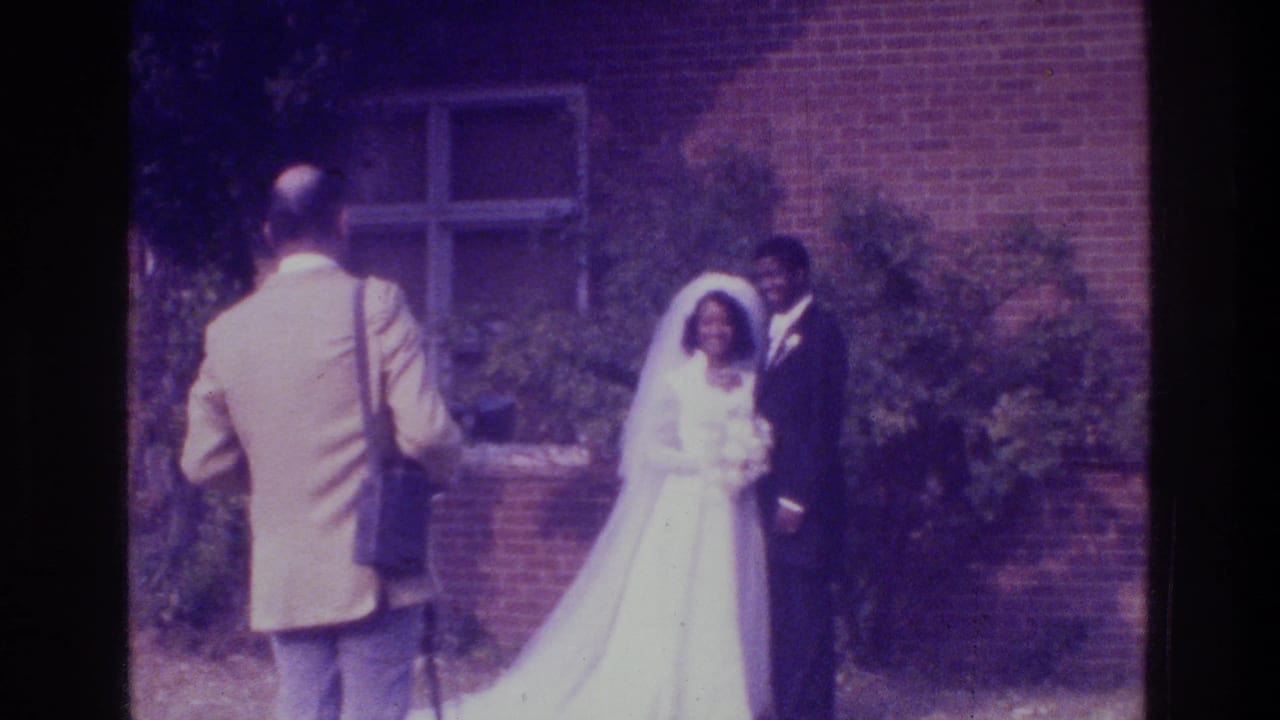 Bride and groom face the camera as the photographer stands in front of them.